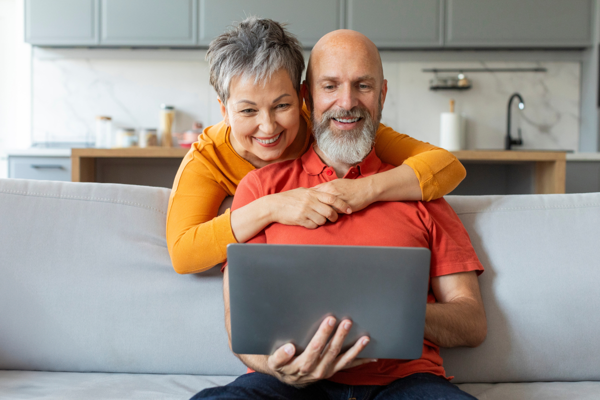 Zwei Privatpersonen schauen zufrieden auf einen Laptop